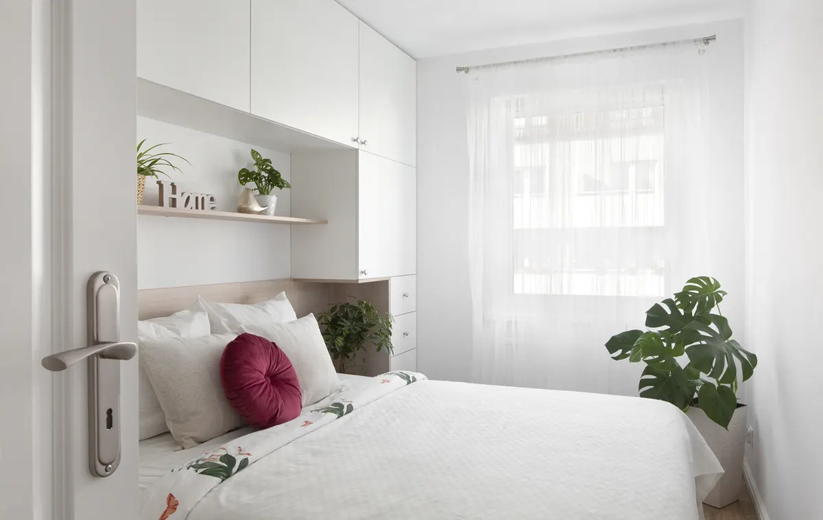 Ta sama sypialnia po home stagingu: biel, rośliny, bordowa poduszka