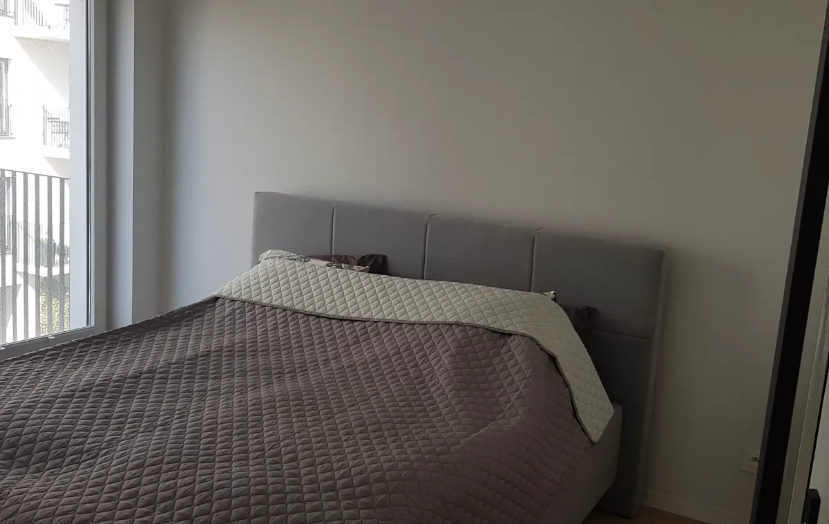 Sypialnia przed home stagingiem: goła ściana, ciemna narzuta
